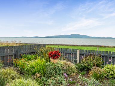 A garden with flowers in a pot overlooking water at Solway View in Skinburness near Silloth