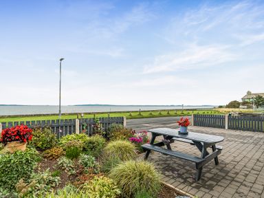 An outdoor seating area with a table and flowers at Solway View in Skinburness near Silloth