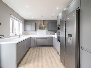 A modern kitchen with grey cabinets stainless steel appliances and light wood flooring at Bryn Hafod in Dyffryn Ardudwy