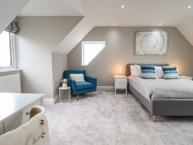 A bedroom with a gray bed and blue armchair at Bryn Hafod in Dyffryn Ardudwy