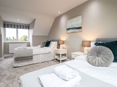A bedroom with two single beds bedside tables lamps and a window at Bryn Hafod in Dyffryn Ardudwy