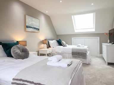 A bedroom with two single beds bedside tables and lamps a skylight and a dresser at Bryn Hafod in Dyffryn Ardudwy
