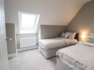 A bedroom with two single beds a bedside table with a lamp a skylight window and a radiator at Bryn Hafod in Dyffryn Ardudwy