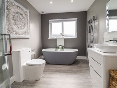 A bathroom with a toilet, freestanding bathtub, vanity with sink, towel radiator, and window at Bryn Hafod in Dyffryn Ardudwy