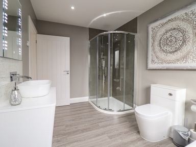 A bathroom with a shower enclosure sink toilet and decorative wall art at Bryn Hafod in Dyffryn Ardudwy