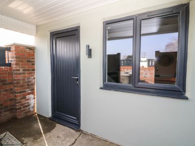 A doorway with a number 1 on the door next to a window with a reflection of outdoor and indoor areas at Chalet 1 in Sherburn