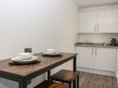 A kitchen area with a wooden table set for two and white cabinets at Chalet 1 in Sherburn