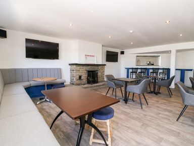 A seating area with tables chairs and a fireplace and two televisions in a room at Chalet 1 in Sherburn