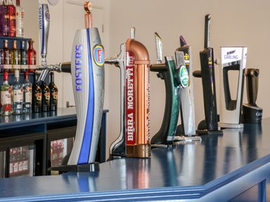 A bar counter with multiple beer taps and bottles on shelves behind at Chalet 1 in Sherburn