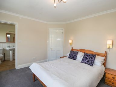 A bedroom with a double bed two bedside tables and an ensuite bathroom at Caradoc Tutshill near Chepstow