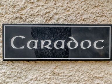A black rectangular plaque with the word Caradoc on a textured wall at Caradoc Tutshill near Chepstow