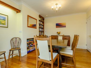 A dining room with wooden table and chairs a sideboard artwork and bookshelf at Caradoc in Tutshill near Chepstow