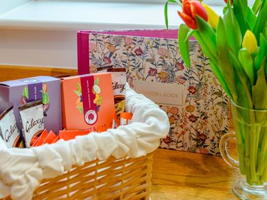 A basket with chocolate bars next to a visitors book and a vase of tulips on a wooden surface at Caradoc Tutshill near Chepstow