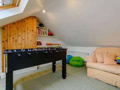 A game room with a foosball table sofa with cushions bean bags and shelves with books and games at Caradoc Tutshill near Chepstow