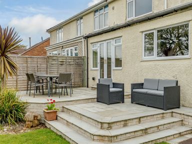 An outdoor patio with a dining table and chairs and a seating area with a sofa and armchair at Caradoc in Tutshill near Chepstow