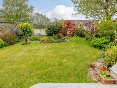 A garden with a lawn surrounded by bushes trees and flowers at Caradoc Tutshill near Chepstow