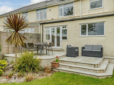 A backyard patio with table and chairs a sofa and plants at Caradoc in Tutshill near Chepstow