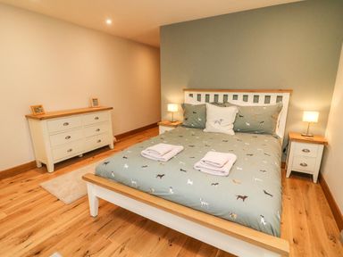 A bedroom with a double bed pillows bedside tables lamps and a dresser at Hollowgill Barn in Sedbergh