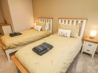 A bedroom with two single beds with giraffe patterned bedding and bedside tables with lamps at Hollowgill Barn in Sedbergh