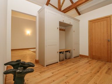 A hallway with wooden floor a white wardrobe wooden door and rubber boots at Hollowgill Barn in Sedbergh