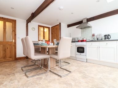 A kitchen with dining table and chairs stove kettle and cabinets at Wheal Prosper@The West Dry in St Austell
