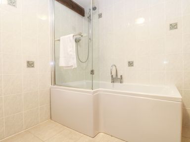 A bathroom with a bathtub shower combination and tiled walls at Wheal Prosper@The West Dry in St Austell