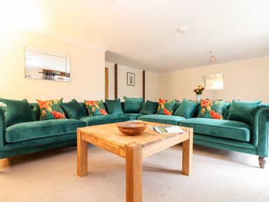 A living room with green sofas and a wooden coffee table at Wheal Prosper@The West Dry in St Austell
