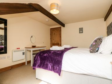 A bedroom with a bed covered in white sheets and a purple blanket at Wheal Prosper@The West Dry in St Austell