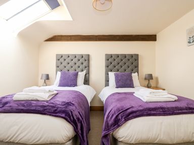 A bedroom with two single beds each with purple throws and pillows at Wheal Prosper@The West Dry in St Austell