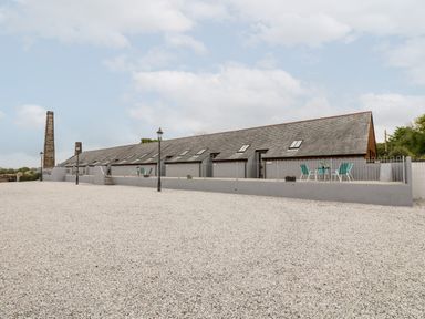 A long building with skylights and outdoor seating on a gravel area at Wheal Prosper@The West Dry in St Austell