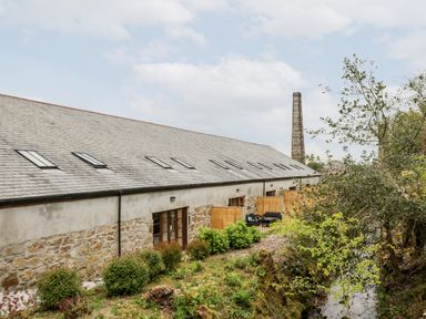 A row of stone and plaster cottages with skylights and fenced patios near a stream at Wheal Prosper@The West Dry in St Austell