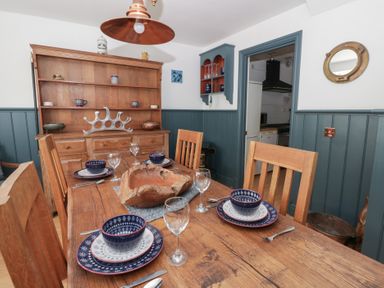 A dining room with a wooden table set for dinner at Awen Ingli Newport, Pembrokeshire
