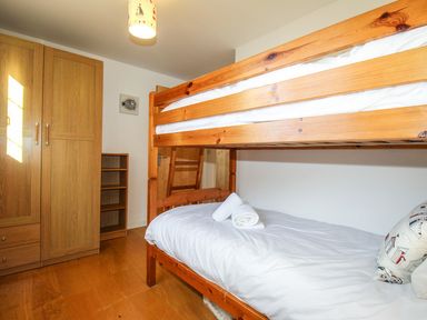 A bedroom with a wooden bunk bed a wardrobe and a small bookshelf at Broadleys Swanage