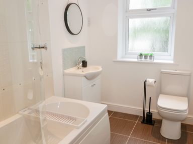 A bathroom with a bathtub shower sink toilet and window at 1 Old Kingdom Hall in Amlwch
