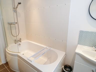 A bathroom with a bathtub shower and sink area at 1 Old Kingdom Hall in Amlwch