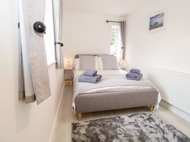 A bedroom with a double bed towels on the bed bedside tables and a rug on the floor at 1 Old Kingdom Hall in Amlwch