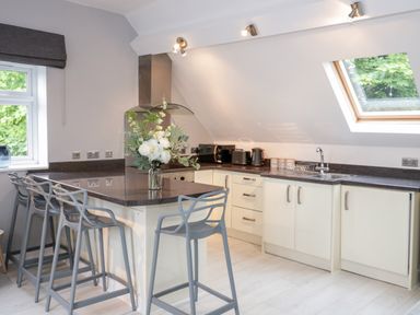 A kitchen with a countertop island with chairs and appliances under a slanted ceiling with skylight at 1 Old Kingdom Hall in Amlwch