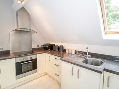 A kitchen with an oven stovetop a sink small appliances and a window at 1 Old Kingdom Hall in Amlwch