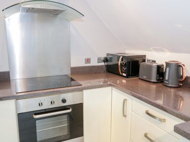 A kitchen corner with a stove oven microwave toaster and kettle at 1 Old Kingdom Hall in Amlwch