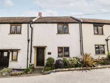 White stone cottages with wooden doors and windows and garden beds in front at Red Roof Marsh near Combe St Nicholas