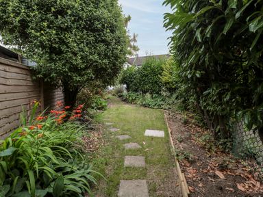 A garden path with stone slabs flanked by plants and trees at Red Roof Marsh near Combe St Nicholas