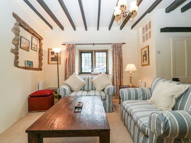 A living room with striped sofas a wooden coffee table and exposed wooden ceiling beams at Red Roof in Marsh near Combe St Nicholas