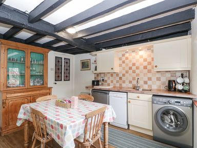 A kitchen with a wooden dining table with four chairs and kitchen appliances at Red Roof Marsh near Combe St Nicholas