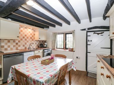 A kitchen with a table covered with a polka dot tablecloth and wooden chairs at Red Roof Marsh near Combe St Nicholas