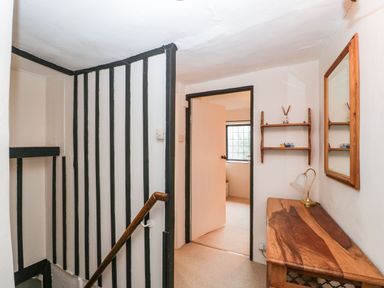 A small hallway with a wooden table and lamp beside a mirror and open door at Red Roof in Marsh near Combe St Nicholas