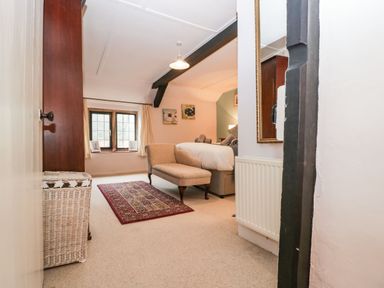 A bedroom with a chaise lounge rug window and bed at Red Roof in Marsh near Combe St Nicholas