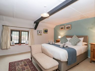 A bedroom with a bed two bedside tables a bench a window and wall decorations at Red Roof Marsh near Combe St Nicholas