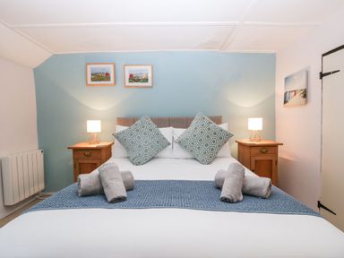 A bedroom with a double bed pillows bedside tables with lamps and framed pictures at Red Roof Marsh near Combe St Nicholas