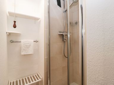 A small tiled shower with glass doors and a towel hanging on a rail in a bathroom at Red Roof Marsh near Combe St Nicholas