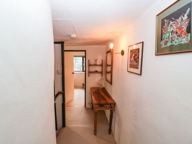 A narrow hallway with wooden table wall light and framed pictures at Red Roof Marsh near Combe St Nicholas